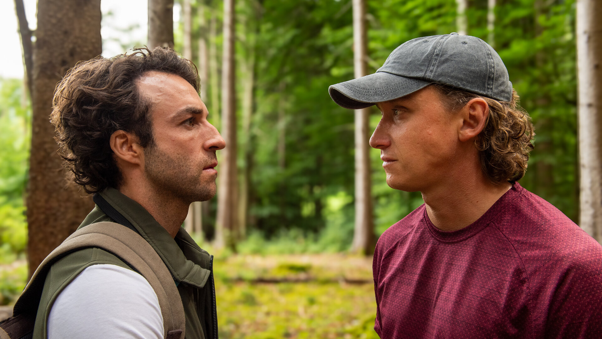 "Baumgeflüster": Yascha (Linus Schütz) und Mats (Aaron Friesz) stehen gemeinsam in einem Wald und schauen sich an.