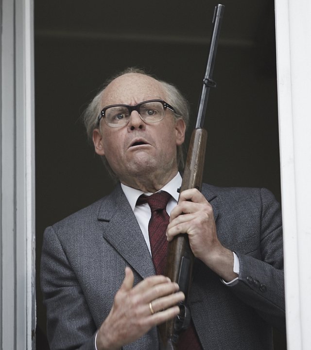 "Sketch History": Max Giermann verkleidet als Erich Honecker. Er steht am offenen Fenster, hält ein Gewehr in der Hand.