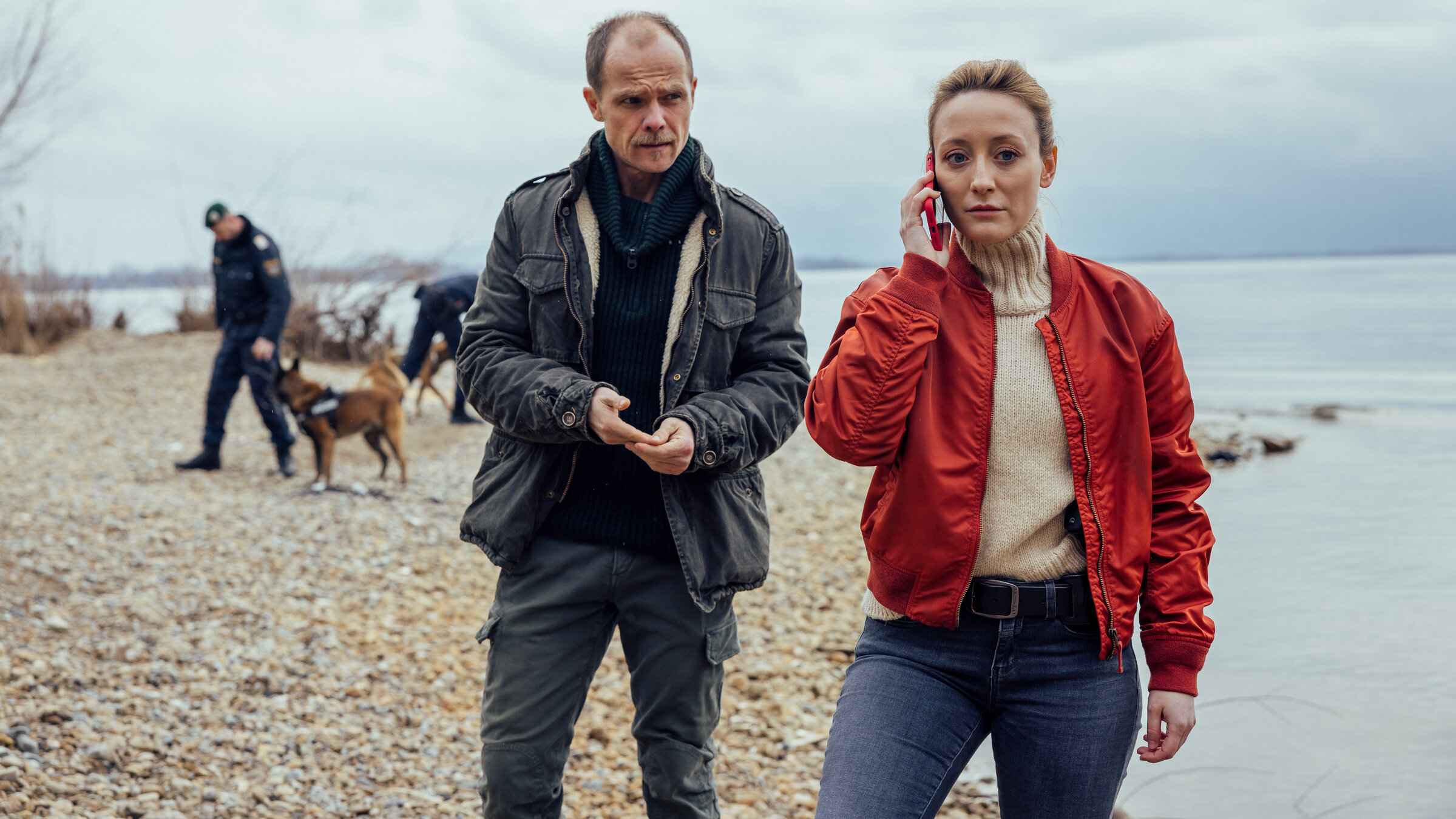 "Die Toten vom Bodensee - Die Medusa": Micha Oberländer (Matthias Koeberlin) und Luisa Hoffmann (Alina Fritsch) stehen zusammen am Ufer. Luisa Hoffmann (Alina Fritsch) telefoniert mit dem Handy.