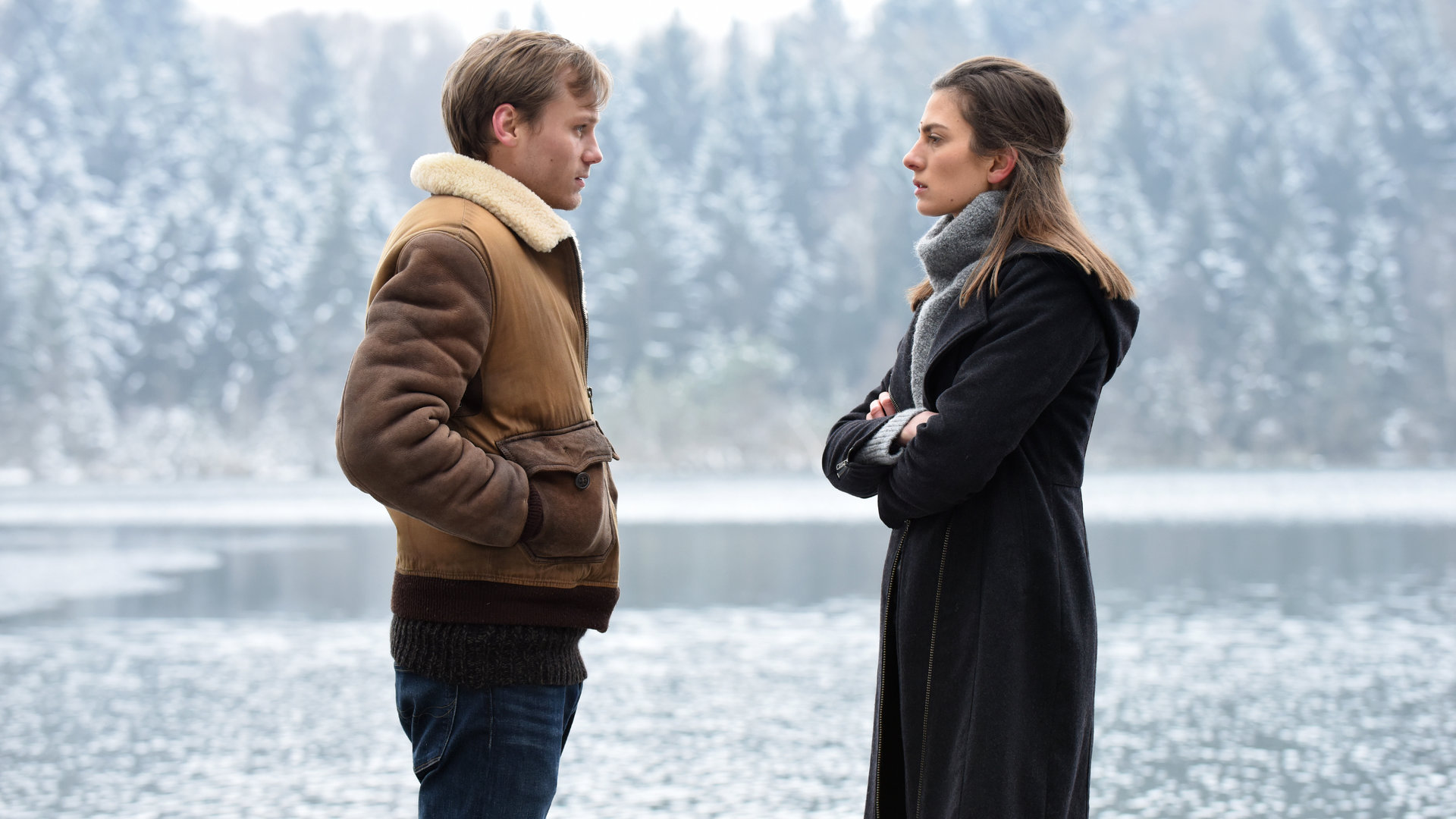 "Winterherz - Tod in einer kalten Nacht ": Mike (Anton Spieker) und Sylvie (Laura de Boer) stehen sich in einer kalten Winterlandschaft gegenüber und schauen sich an. Im Hintergrund ein See.