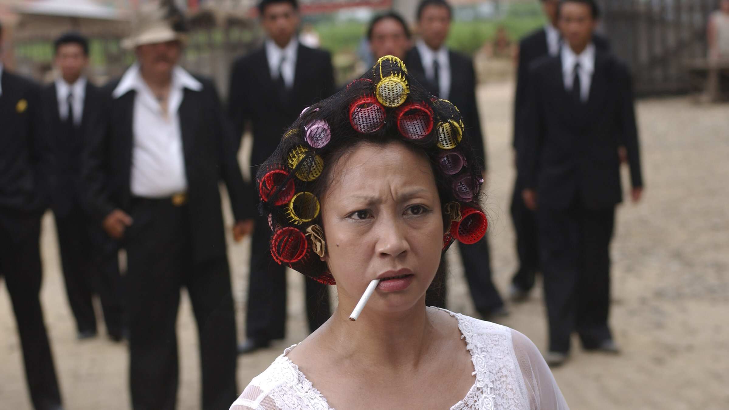 "Kung Fu Hustle": Auf einem Dorfplatz steht die Landlady (Qiu Yuen) im Nachthemd, mit Lockenwicklern im Haar und einer Zigarette im Mund. Hinter ihr haben sich die Männer der Axt-Gang versammelt.