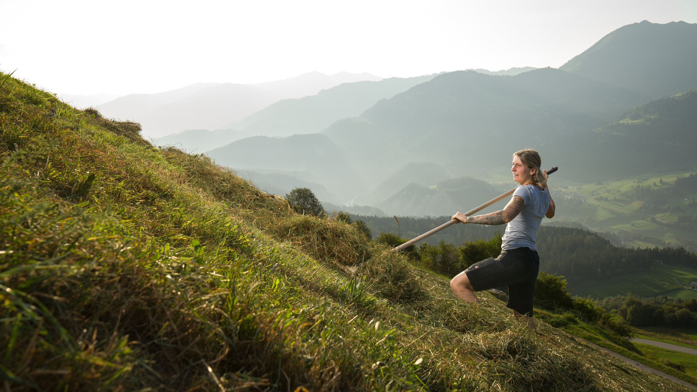 "37°Leben: Raus aus dem Job - Neuanfang in den Bergen": Lesly recht auf einer Bergwiese Gras zusammen.