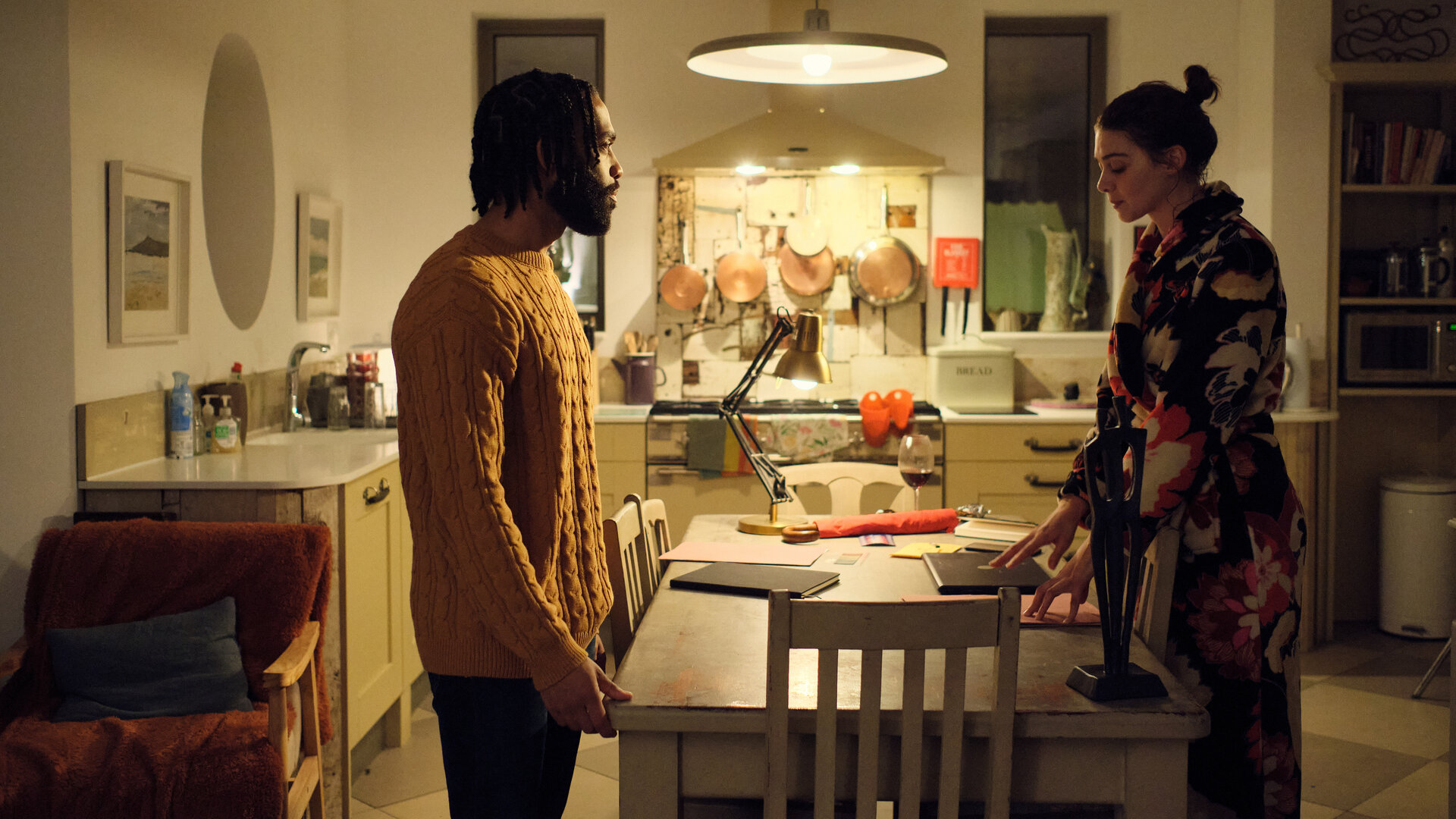 "The Killing Kind: Schatten der Vergangenheit": Ingrid (Emma Appleton) und ihr Verlobter Mark (Elliot Barnes-Worrell) stehen sich in ihrer Küche an ihrem Küchentisch gegenüber. Sie blicken ernst.