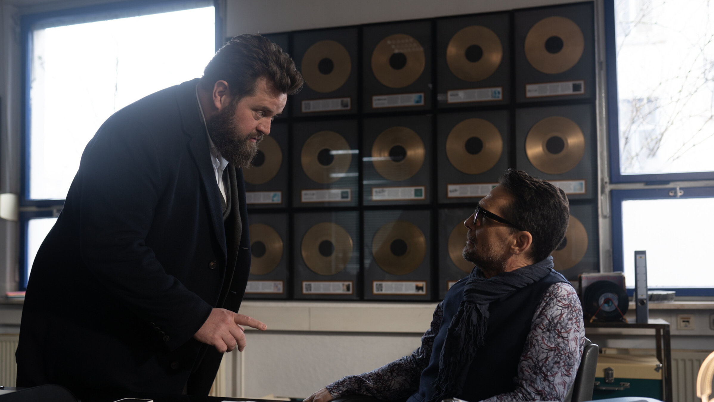"Ein Fall für zwei - Showbizz": Benjamin Hornberg (Antoine Monot) steht neben Lennart Parker (Robert Seeliger), der im Büro seines Plattenstudios am Schreibtisch sitzt. Benni redet mit ernstem Gesichtsausdruck auf ihn ein.