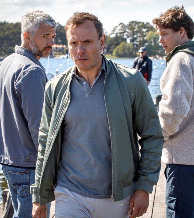 "Mord im Mittsommer - Lili": Alexander (Nicolai Cleve Broch) und sein Kollege Welpe (Julius Fleischanderl) stehen an einem  Bootssteg und schauen verwundert dem Star Golfer Theo Skoog (Björn Bengtsson) hinterher.