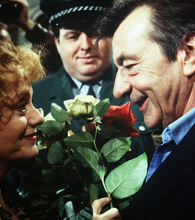"Alle meine Töchter - Realitätsverlust": Berthold Sanwald (Günter Mack) und Frau Haase (Billie Zöckler) stehen sich gegenüber, er überreicht ihr freudig ein paar Blumen.