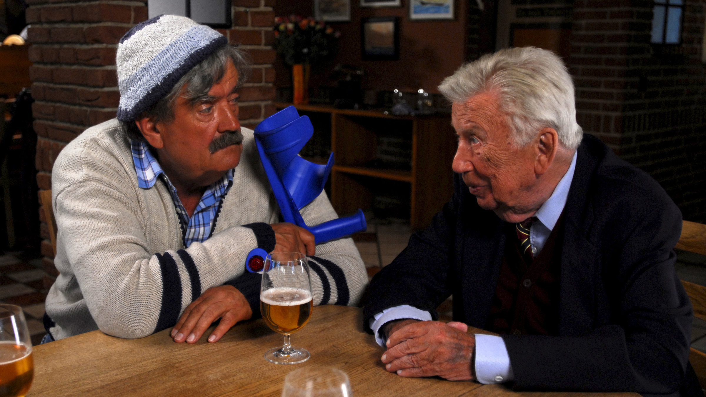 "Der Landarzt - Reine Nervensache": Hinnerksen (Gerhard Olschewski) und Albert Eckholm (Heinz Reincke) sitzen zusammen an einem Tisch in einem Lokal. Es steht Bier auf dem Tisch.