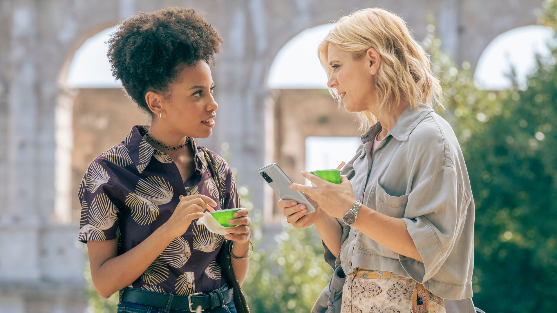 "Signora Volpe - Verkannte Helden": Raffaella (Marianne Leoni) und Sylvia (Emilia Fox) stehen sich vor dem Kolosseums in Rom gegenüber. Beide halten Eisbecher in der Hand, Sylvia zudem noch ihr Mobiltelefon.