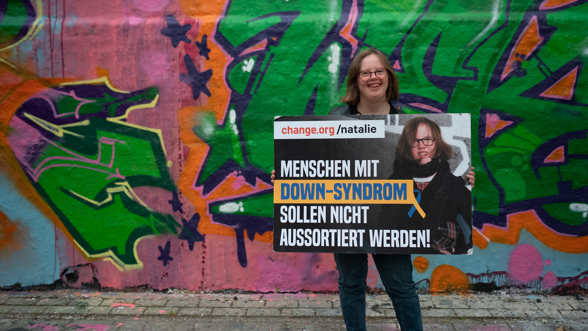 "einfach Mensch: Natalie Dedreux - Trisomie 21, so what!": Natalie Dedreux hält ein Schild auf dem steht, dass Menschen mit Downsyndrom nicht aussortiert werden dürfen.
