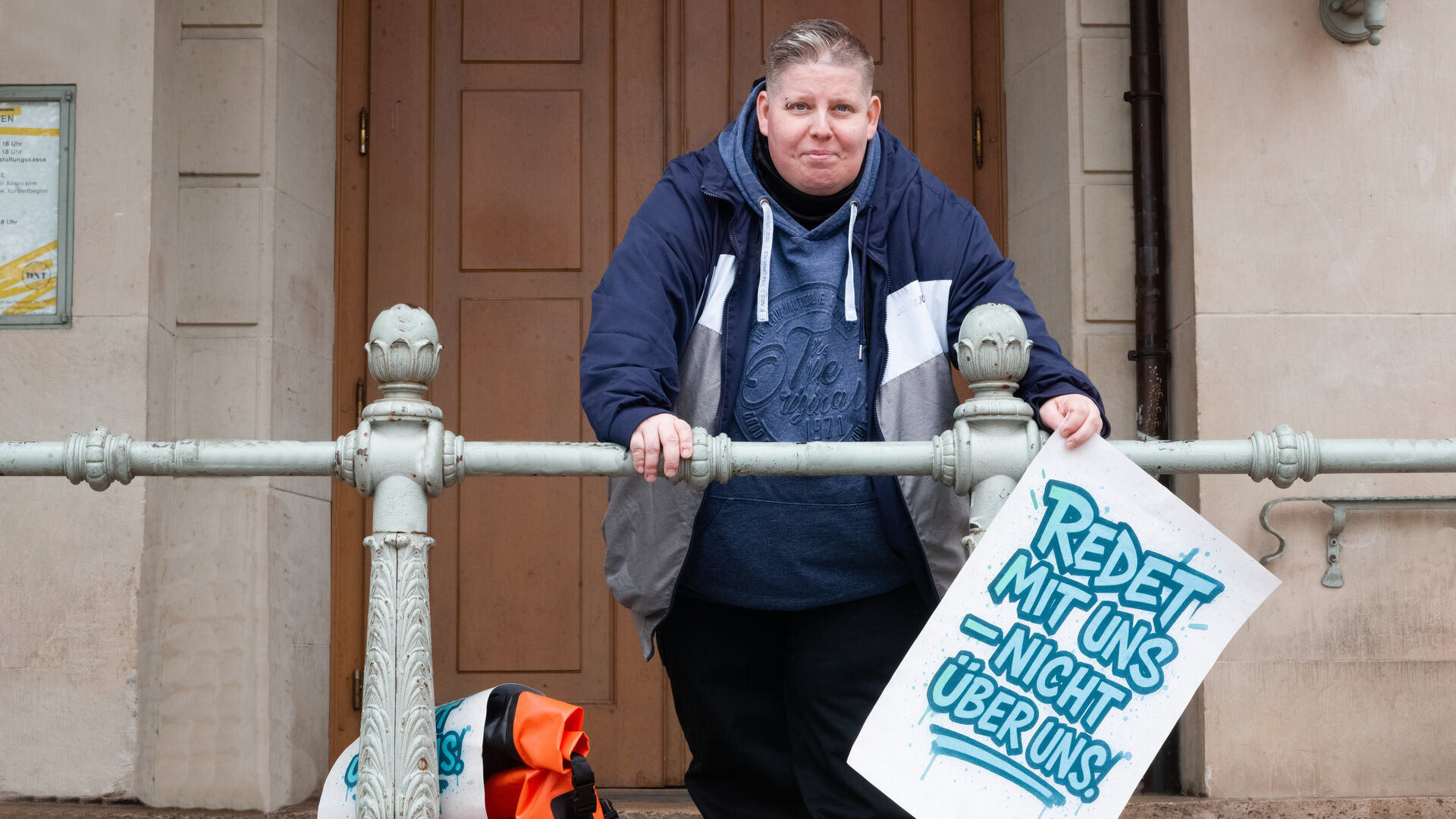 "einfach Mensch - Nancy Frind: Redet mit, nicht über uns": Nancy Frind hält Plakat mit der Aufschrift „Redet mit uns – nicht über uns.“