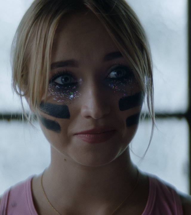 "Derby Girl - Auge um Auge...": Lola (Chloé Jouannet) steht vor einer hellen Fensterfront und schaut entschlossen in die Ferne. Dabei trägt sie Sportkleidung und hat Kampfbemalung im Gesicht.