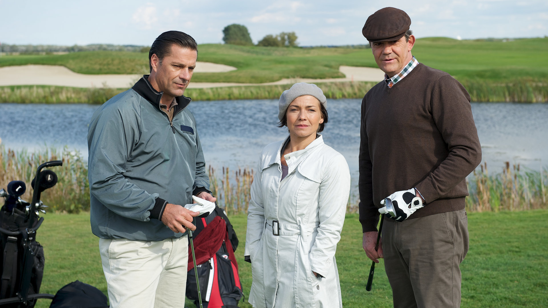 "SOKO Wismar - Eingelocht": Vor einem See auf dem Golfplatz im Gras stehen Hein (Dirk Schoedon), Katrin Börensen (Claudia Schmutzler) und Piet (Andreas Krätzig) nebeneinander.