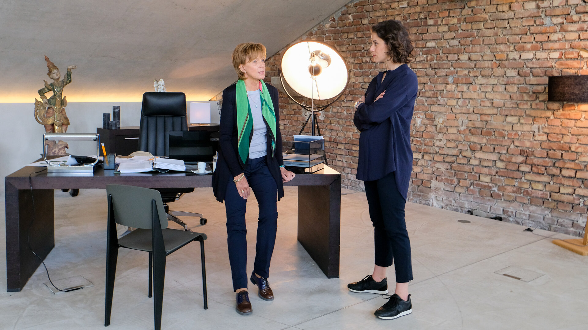 "Lena Lorenz - Kind da, Job weg": In einem Loft ähnlichen Büro stehen Brigitte Albrecht (Ulrike Kriener) und Constanze Bergmann (Anne Schäfer) vor einem eleganten Holzschreibtisch und unterhalten sich.