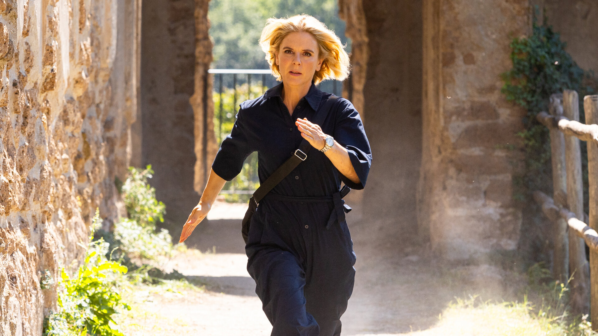 "Signora Volpe - Ehrenschuld": Sylvia Fox (Emilia Fox) läuft schnell über einen Weg. Neben und hinter ihr stehen die Gemäuer einer Burgruine.