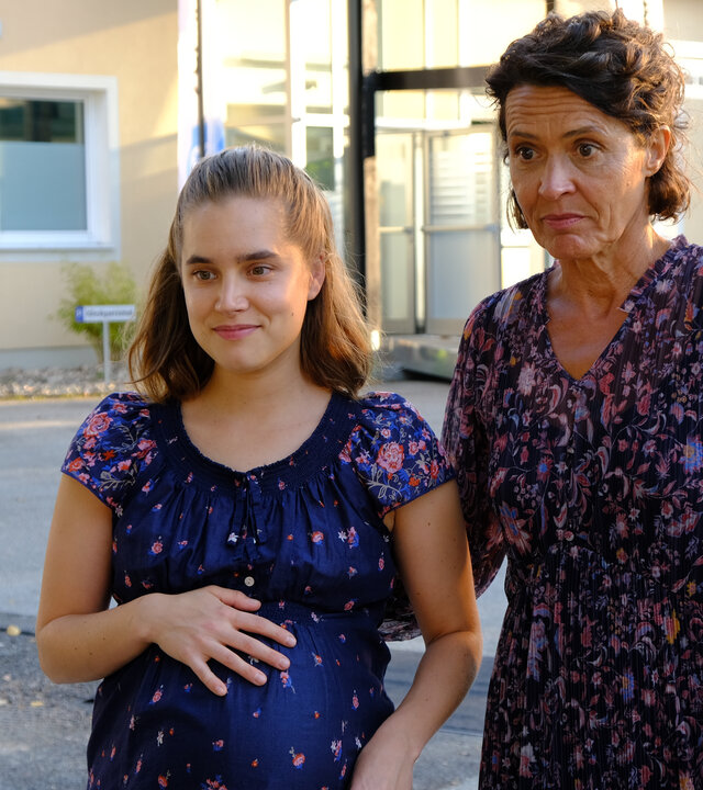 "Lena Lorenz - Baby auf Probe": Vor dem Eingang zum Krankenhaus stehen Regine Moosleitner (Ulrike Folkerts) und ihre hochschwangere Tochter Alina (Anne-Marie Lux) nebeneinander.