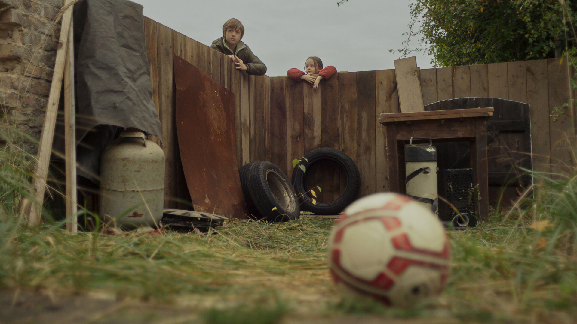 "Doktor Ballouz - Helden": Daniel (Marian Dilger) und seine Schwester Zoé (Elise Lindner) blicken vom Zaun aus auf den Fußball, der auf dem Nachbarsgrund gelandet ist.