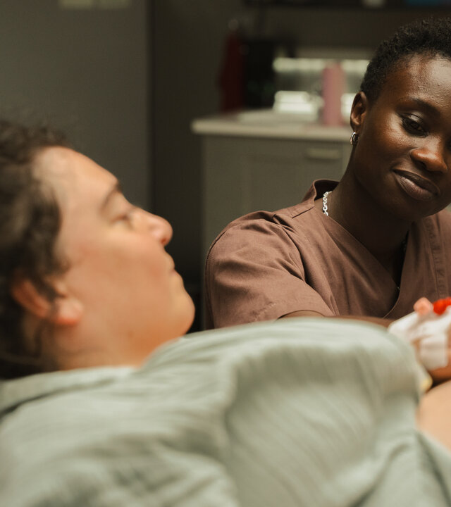 "PUSH - Akzeptanz": Sibel (Nuriye Jendroßek) liegt im Patientenbett und schaut zu Tara (Lorna Ishema), die an ihrem Bett sitzt und eine Hand auf Sibels Babybauch legt. Sibel hält Taras Hand.