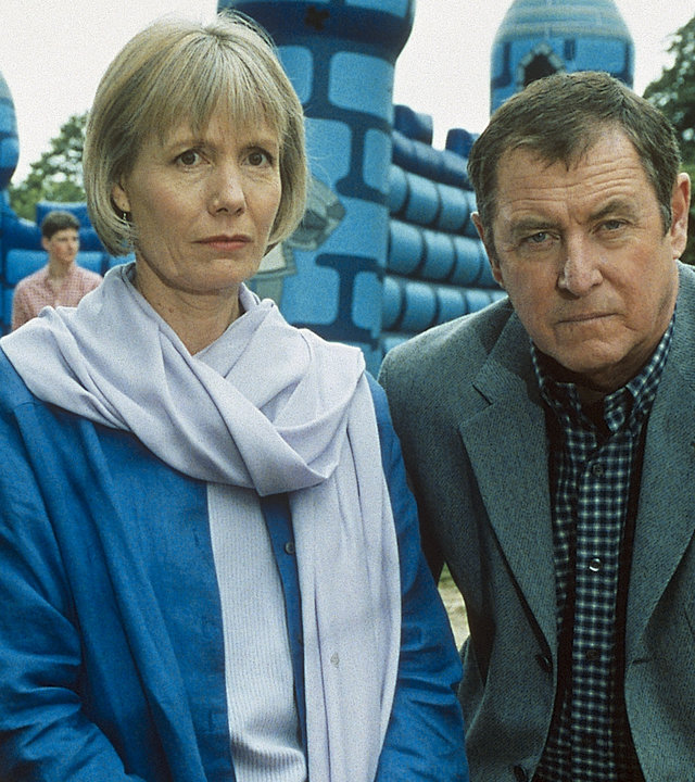 "Inspector Barnaby - Trau, schau, wem!": Inspector Tom Barnaby (John Nettles) und seine Frau Joyce (Jane Wymark) in Großaufnahme. Sie befinden sich auf einer Veranstaltung. Im Hintergrund ist eine Hüpfburg zu sehen.