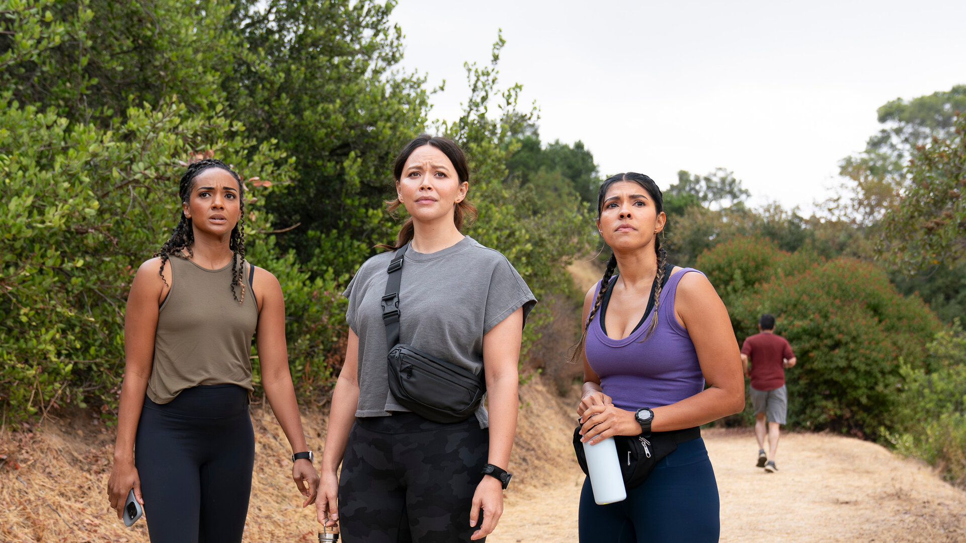 "The Rookie - Das Feuer": Detective Nyla Harper (Mekia Cox), Officer Lucy Chen (Melissa O'Neil) und Celina Juarez (Lisseth Chavez) stehen nebeneinander auf einem Weg in den Hollywood Hills. Alle tragen sportliche Kleidung und blicken fragend in dieselbe Richtung. Chen und Juarez halten jeweils eine Trinkflasche in den Händen.