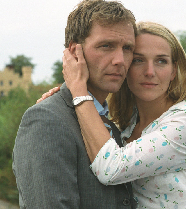 "Bianca - Wege zum Glück: Kapitel 103": Im Park: Oliver (Patrick Fichte) und Bianca (Tanja Wedhorn) umarmen sich. Bianca drückt ihren Kopf an Olivers Kopf und legt ihre linke Hand an Olivers Wange. Im Hintergrund steht eine unbekannten Person. Oliver wirkt sehr traurig.