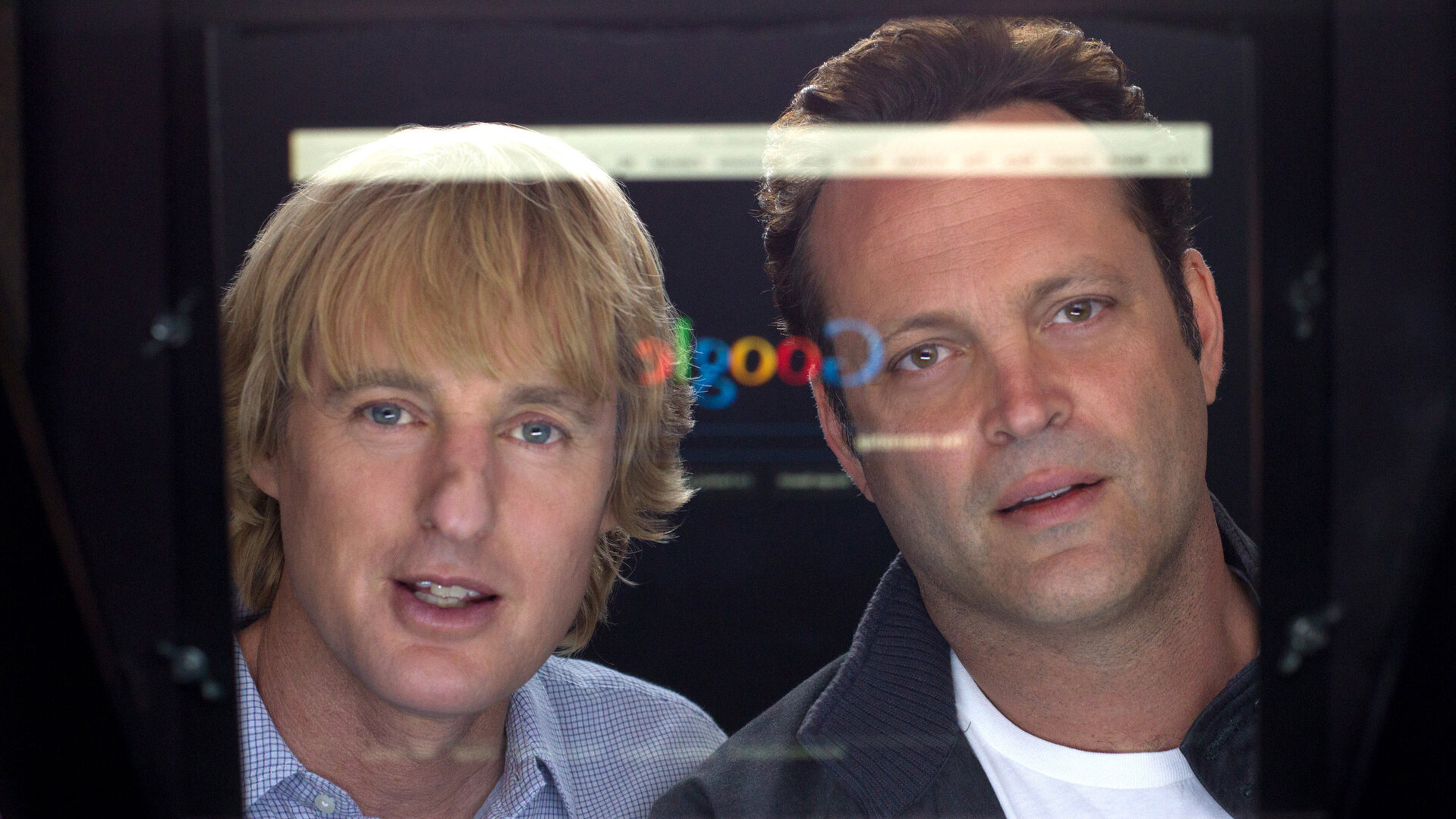 "Prakti.com": Nick (Owen Wilson) und Billy (Vince Vaughn) starren fasziniert auf einen PC-Bildschirm, auf dem die Google-Suchleiste und ihr eigenes Spiegelbild sichtbar sind.