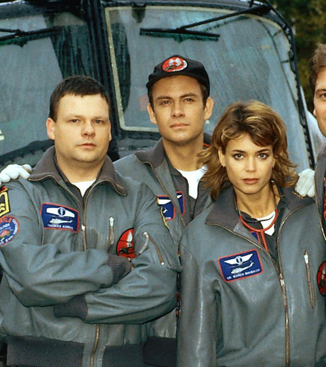 "Die Rettungsflieger - Der Schock": Bordmechaniker Wollcke (Oliver Hörner), Thomas (Ulrich Bähnk), Maren (Gerit Kling) und Alex (Matthias Leja) stehen nebeneinander vor dem Rettungshubschrauber und blicken in die Kamera.