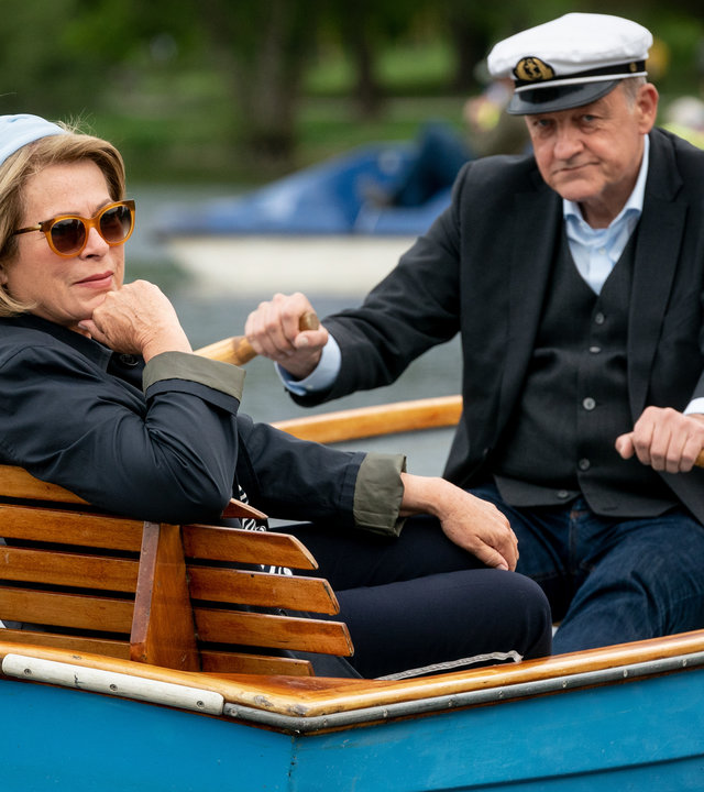 "Wilsberg - Schutzengel": Anna Springer (Rita Russek) sitzt in einem Holzboot auf dem Aasee und überlässt Georg Wilsberg (Leonard Lansink) das Rudern.