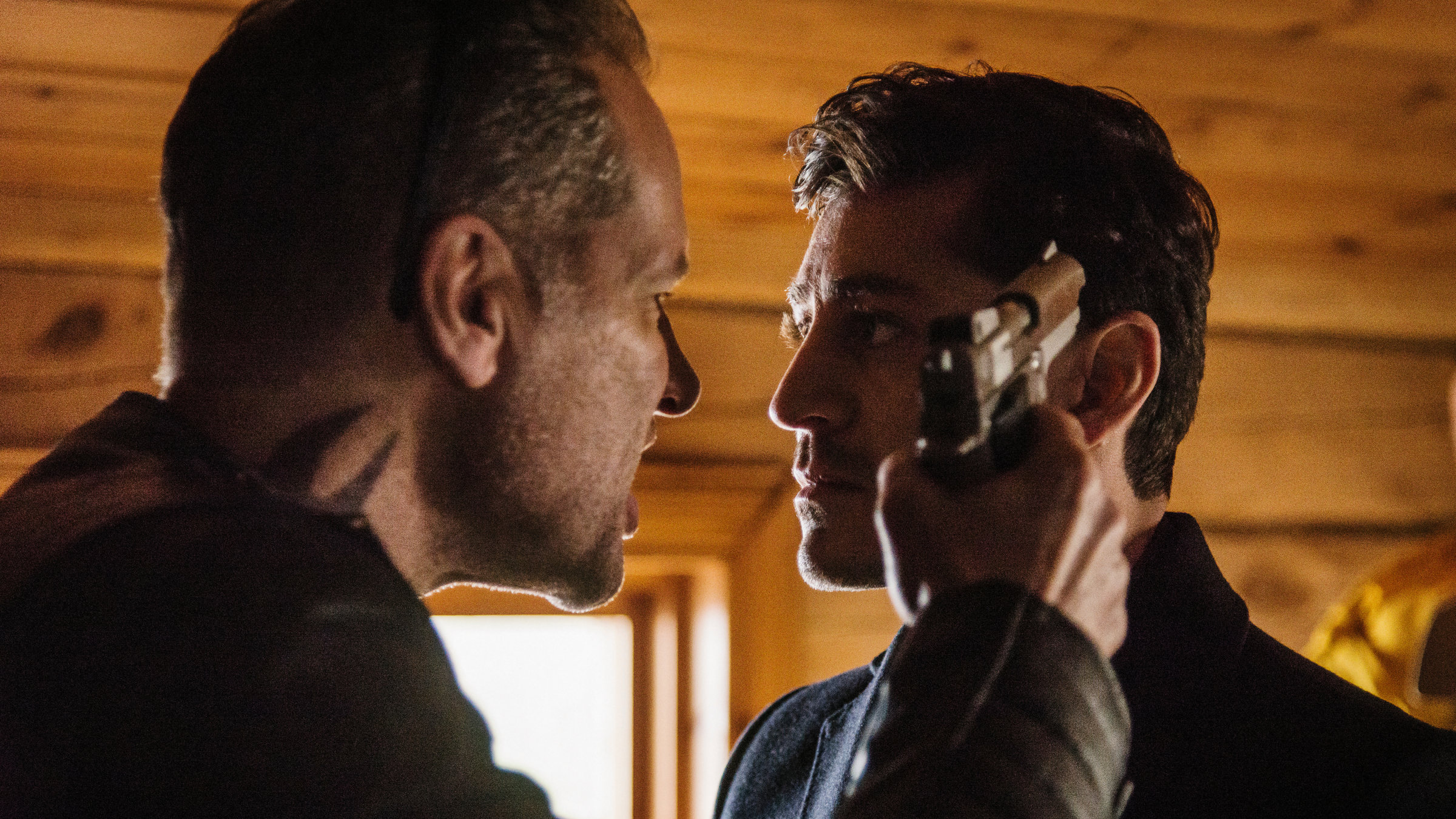 "Hanna Svensson - Blutsbande": Rockerboss Ulrik (Felix Engström) bedroht Davor Mimica (Alexej Manvelov) in einer Holzhütte. Er hält ihm eine Waffe an die Schläfe.