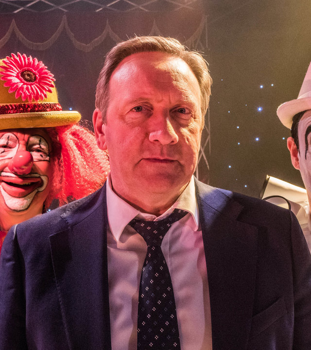 "Inspector Barnaby - Ein Mords-Zirkus": John Barnaby (Neil Dudgeon) steht zwischen den Clowns Les "Oucho" Morrison (Mike Grady) und Terry "Groucho" Bellini (Kevin Eldon) in einer Zirkusmanege. Alle schauen in die Kamera.