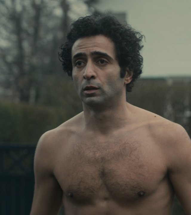 "Unseen - Infiziert": Ayoub Griyeb (Roda Fawaz) steht ohne Oberteil in einem Vorgarten und schaut besorgt drein.
