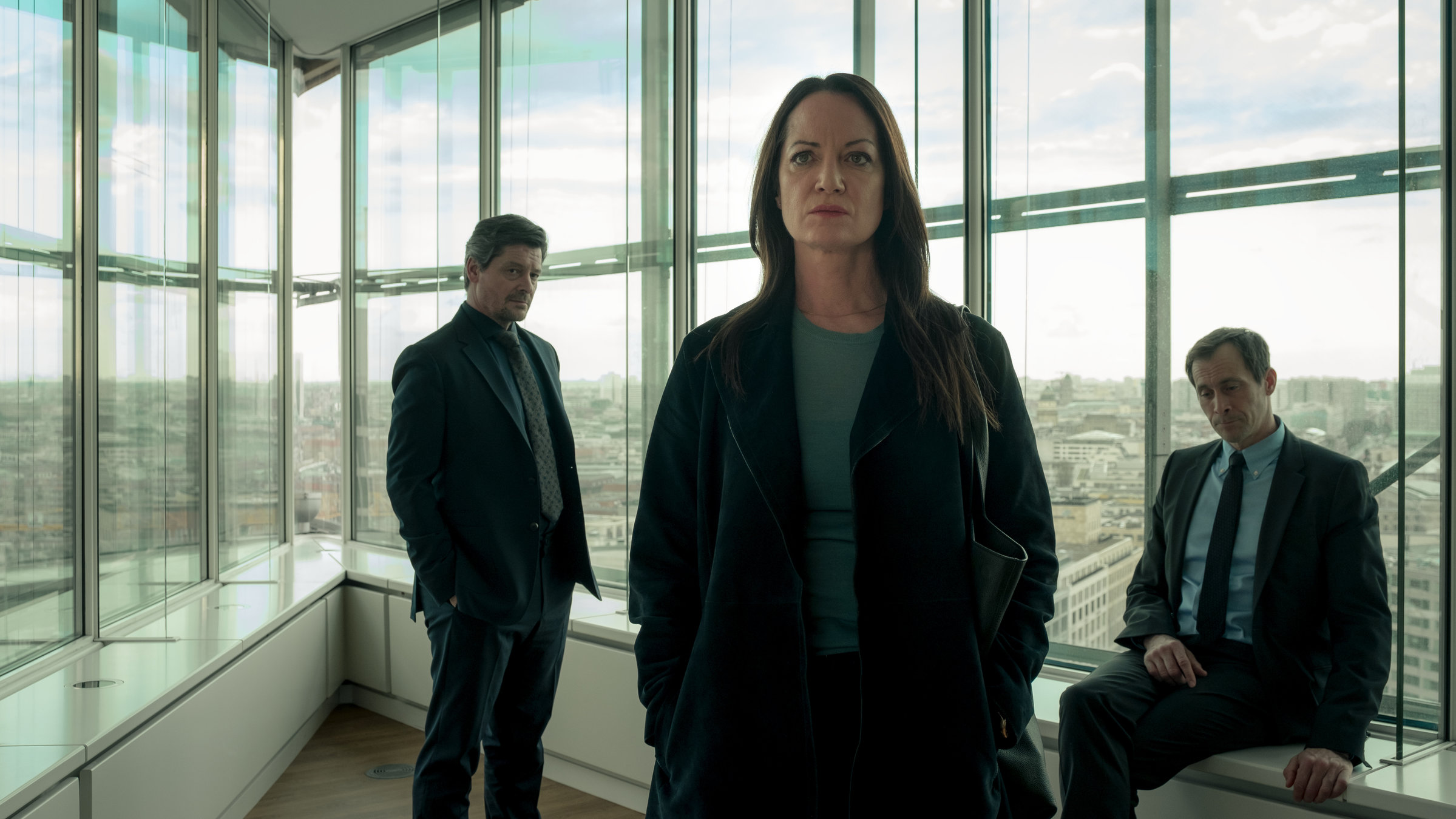 "Wahrheit oder Lüge": Annabelle (Natalia Wörner) steht in einem Büro und schaut in die Ferne. Hinter ihr befindet sich John (Fritz Karl), der sie ansieht. Tom (Marc Hosemann) sitzt auf der Fensterbank und starrt unter sich.