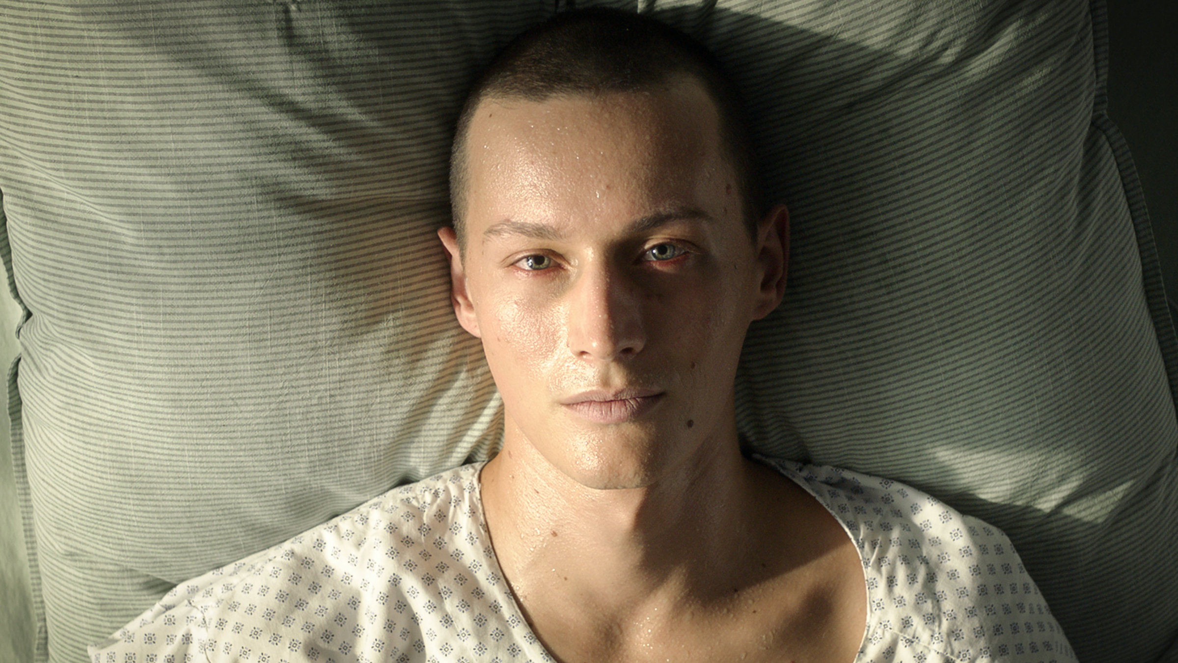 "Doktor Ballouz - Tunnel": Blick von oben: Matti (Lennart König) liegt auf dem Rücken im Krankenbett. Sein Gesicht ist von Schweißperlen überzogen.