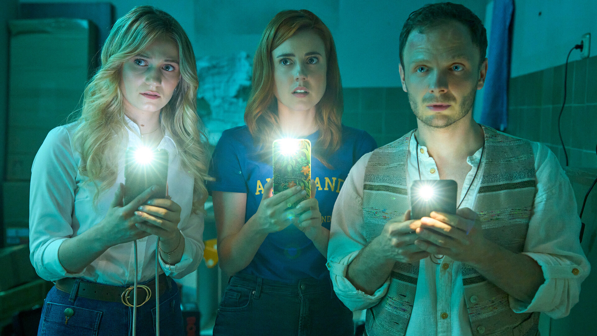 "Ich dich auch! - Der Dichtungsring": Svenja (Leonie Wesselow), Caro (Meriel Hinsching) und Hauke (Fabian Baecker) stehen im dunklen Raum nebeneinander und schauen erstaunt nach vorne. Dabei halten alle drei ihre Handys und leuchten damit nach vorne.