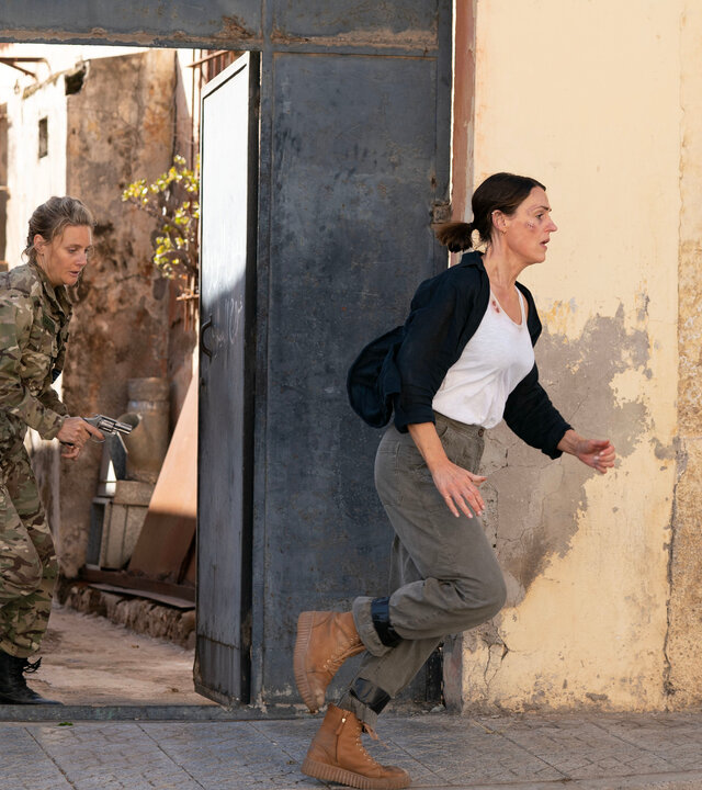 "Vigil - Tödliche Drohnen: Entführt": Eliza Russell (Romola Garai) und Amy Silva (Suranne Jones) rennen dicht hintereinander durch ein geöffnetes Eisentor.