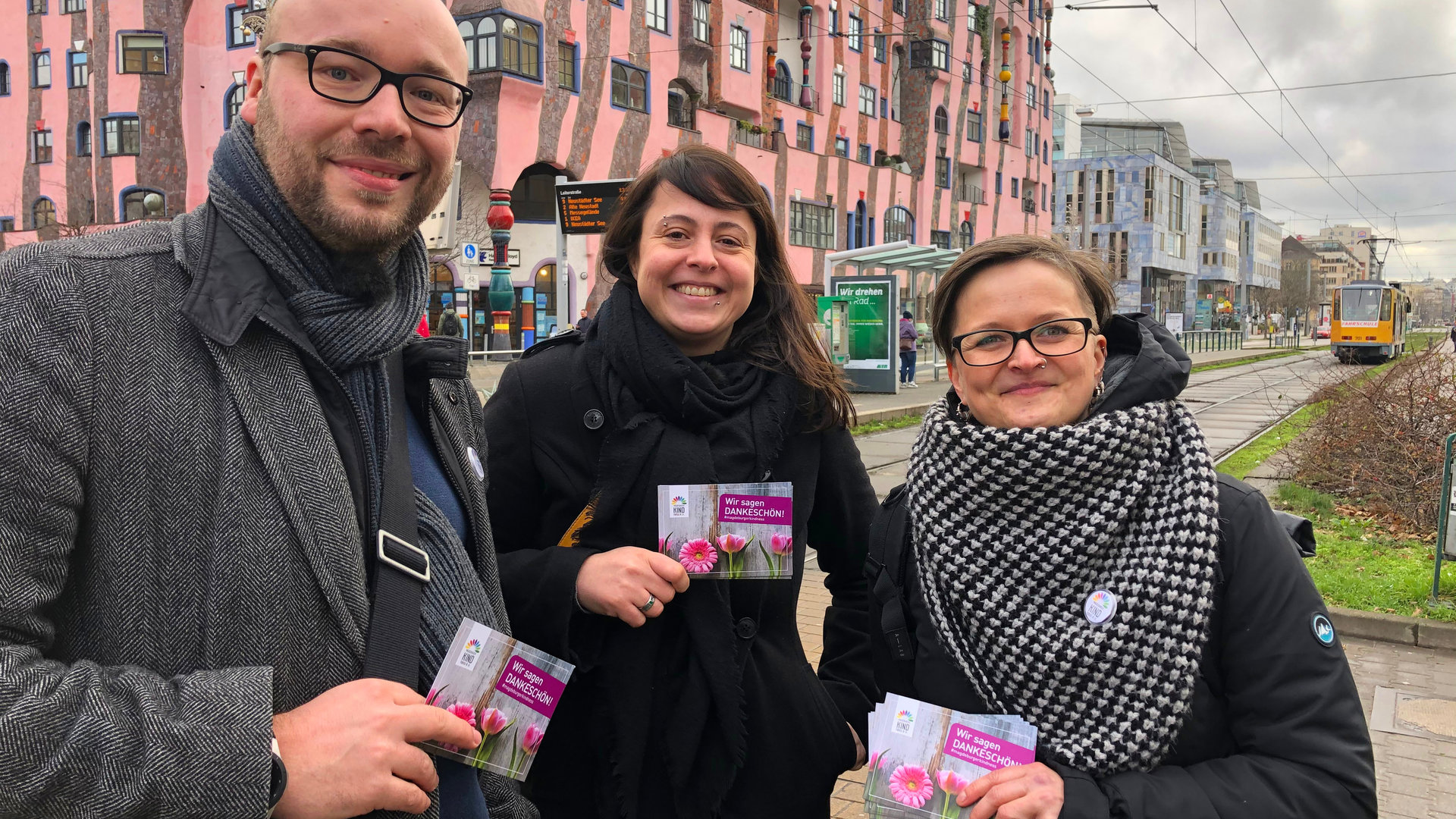 "plan b: Zurück zur Freundlichkeit - Der Kampf gegen den Hass": Ein Mann und zwei Frauen stehen vor Straßenbahngleisen, im Hintergrund ein Gebäude.