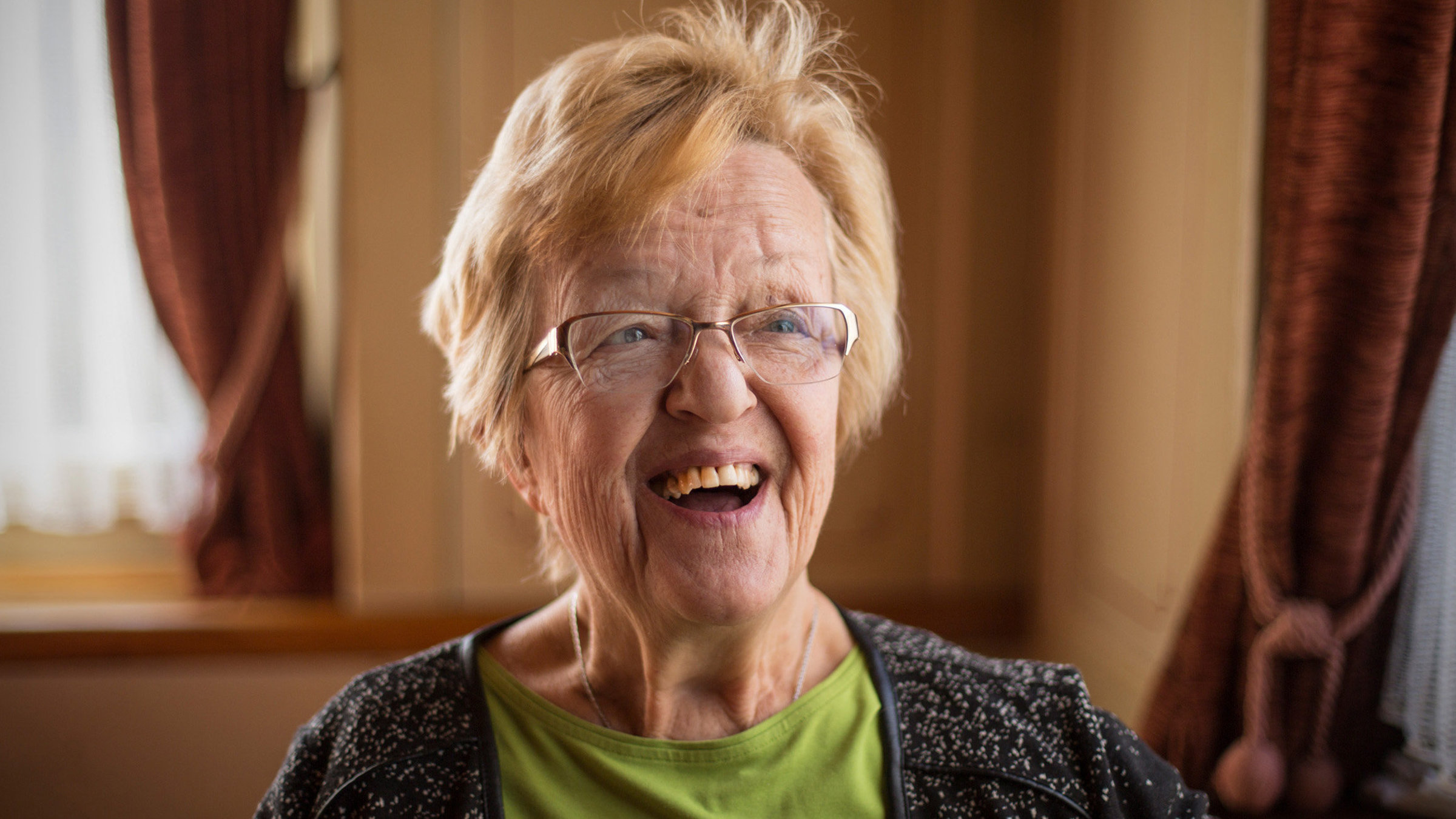 "Klein gewachsen – Wirtin Olga Jutzeler trotzt ihrem Schicksal": Porträtfoto von Olga Jutzeler, lachend