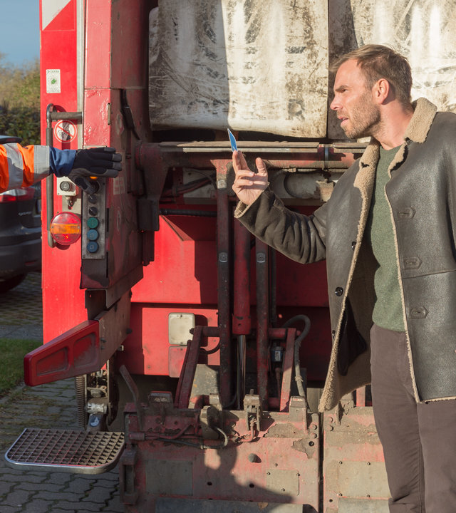 "SOKO Wismar – Für die Tonne": Lars Pöhlmann (Dominic Boeer) und Robert Ohlsen (Marius Borghoff) stehen hinter einem Müllfahrzeug auf der Straße. Lars hält Ohlsen seinen Dienstausweis hin.