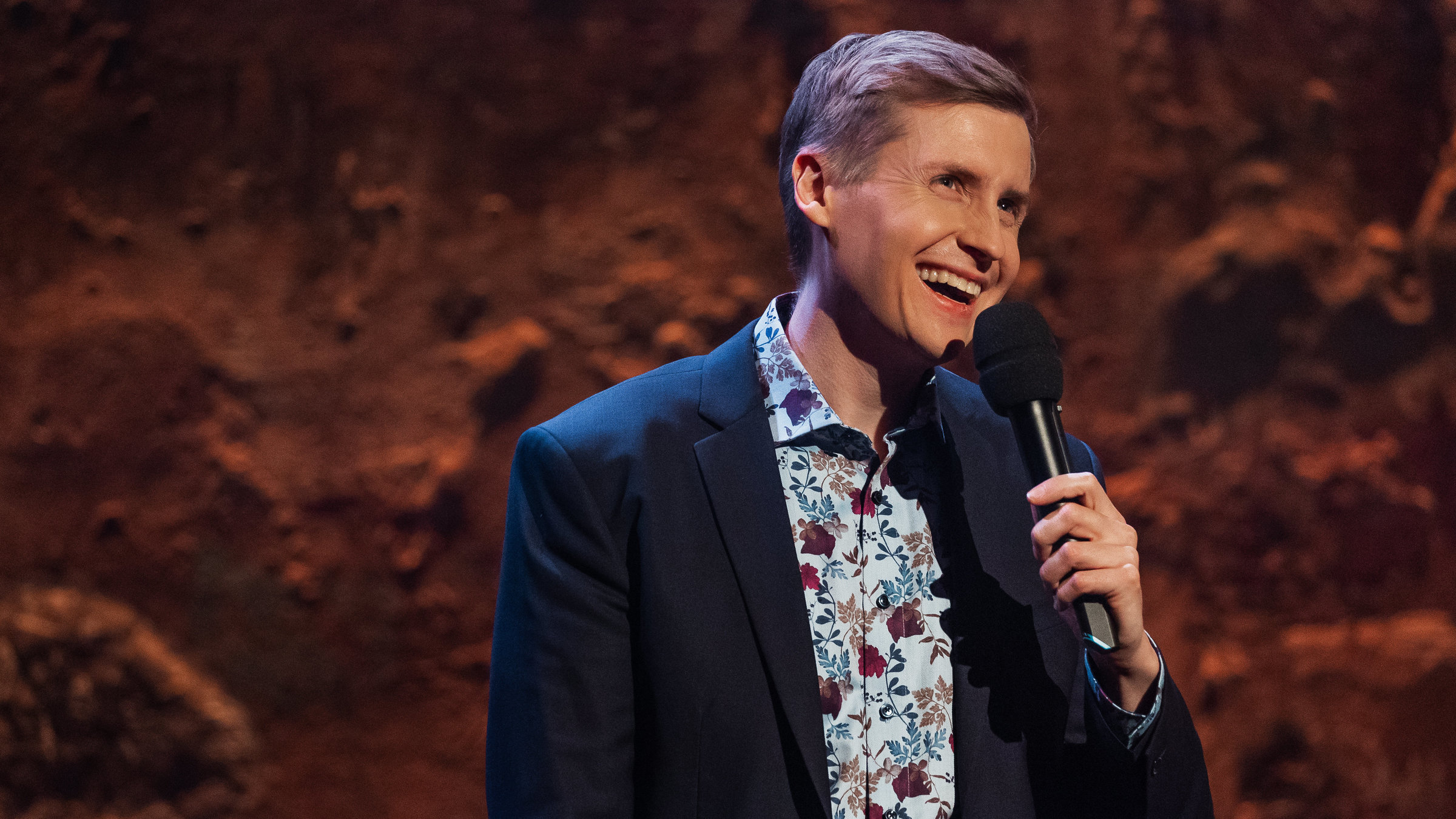 "Till Reiners´ Happy Hour": Der Moderator Till Reiners steht auf der Bühne und unterhält lachend sein Publikum.