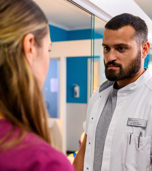 "Bettys Diagnose - Alles anders": Dr. Şahin (Nicolas Fethi Türksever) steht Betty (Henrike Hahn) im Krankenhaus gegenüber und schaut sie an.