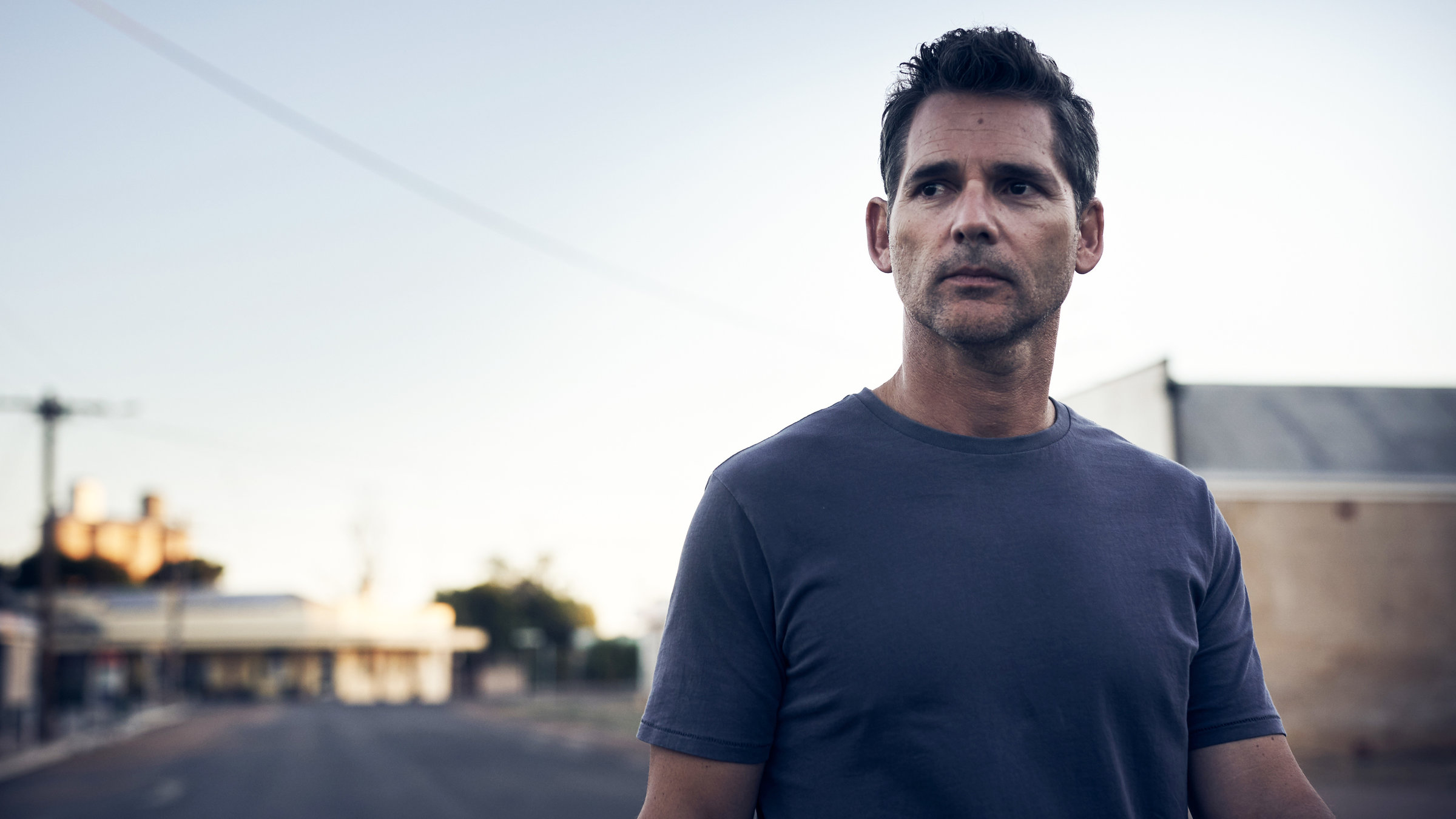 "The Dry - Lügen der Vergangenheit": Aaron Falk (Eric Bana) steht auf einer Straße und schaut kritisch zur Seite.