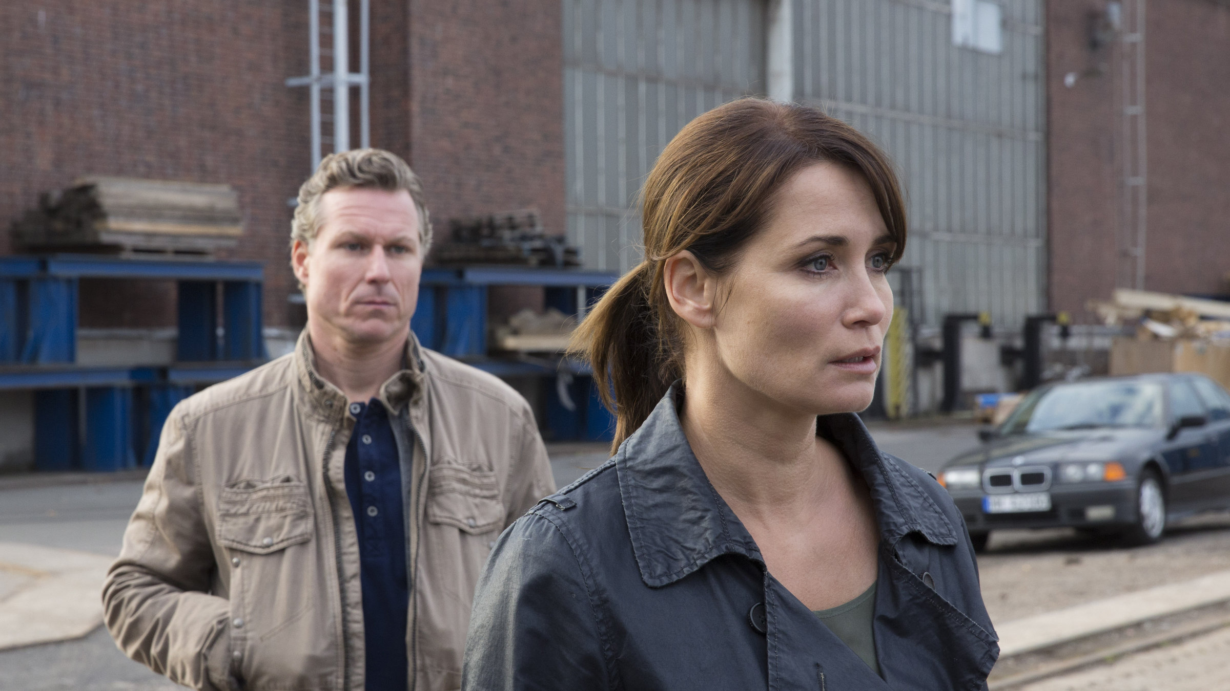 "Verhängnisvolle Nähe": Karin Meister (Anja Kling) und ihr Kollege Mike (Dirk Borchardt) stehen in einem Industriegebiet vor einem Gebäude. Sie hat ihm den Rücken zugewandt.