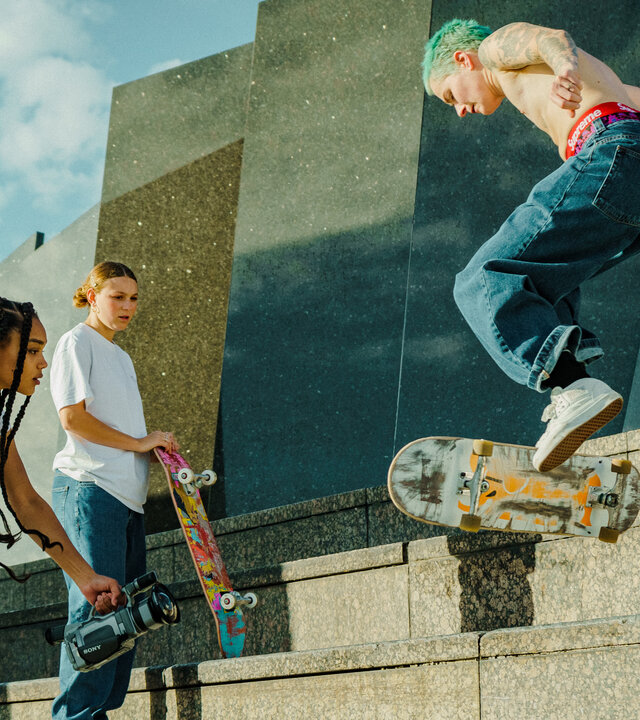 "Die feige Schönheit": MAY (Sira-Anna Faal), FANNI (Lea Meny), KESSE (Pascale Numan) beim Skateboarden vor einer Treppe, wobei MAY alles mit einer Filmkamera dreht