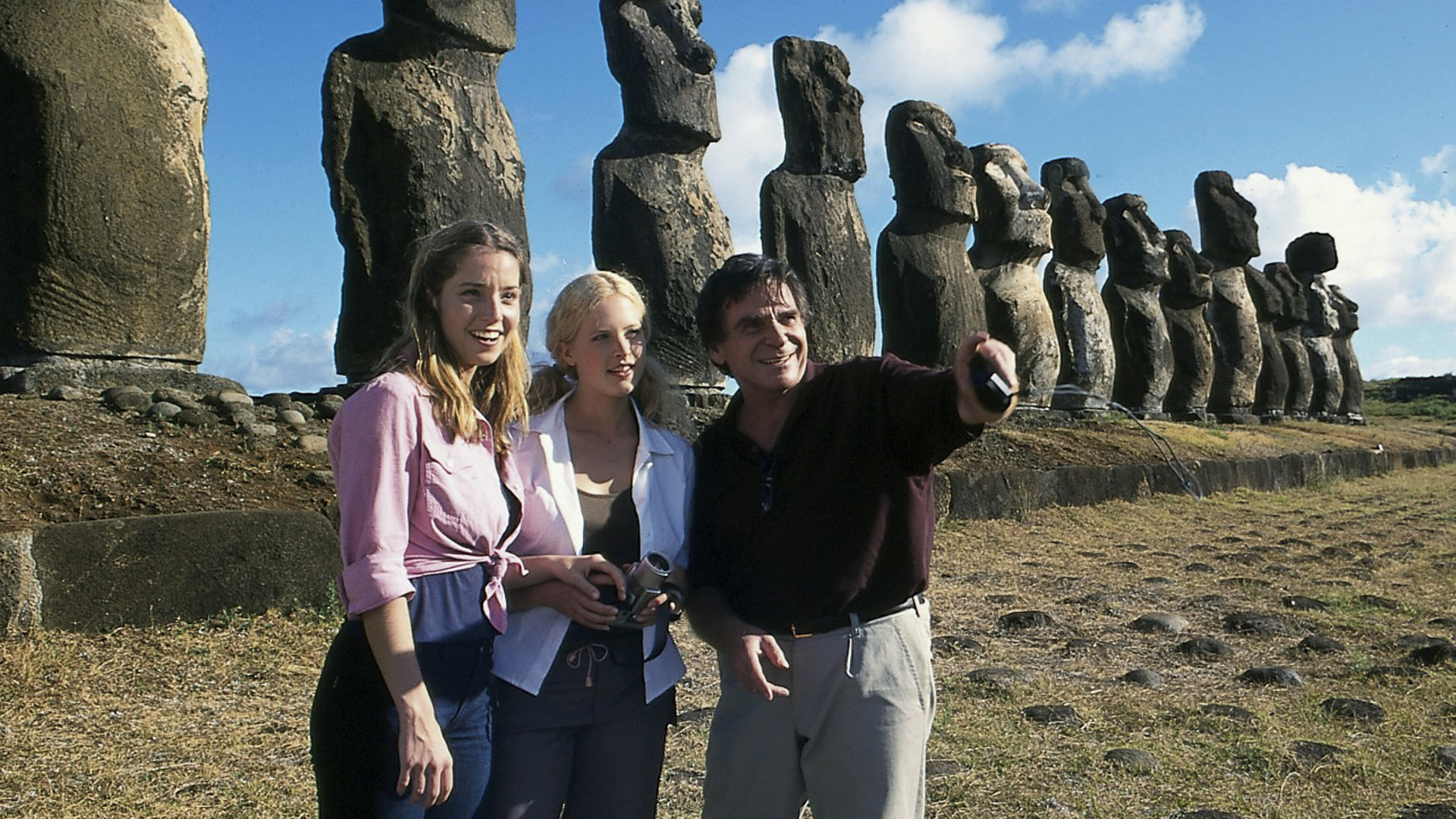 "Das Traumschiff: Chile und die Osterinseln": Johannes (Elmar Wepper), Patricia (Diana Amft) und Nicola (Jana Leipziger) stehen nebeneinander vor einem der Wahrzeichen Chiles: den Ahu Tongariki - Steinstatuen. Johannes zeigt mit dem Finger in eine Richtung. Alle lächeln.