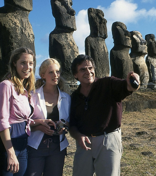 "Das Traumschiff: Chile und die Osterinseln": Johannes (Elmar Wepper), Patricia (Diana Amft) und Nicola (Jana Leipziger) stehen nebeneinander vor einem der Wahrzeichen Chiles: den Ahu Tongariki - Steinstatuen. Johannes zeigt mit dem Finger in eine Richtung. Alle lächeln.