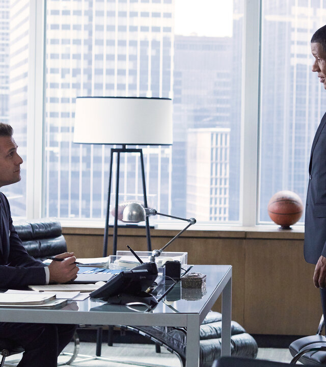 "Suits - Schuldeingeständnis": James Palmer (Scott Lawrence) steht dem am Schreibtisch sitzenden Harvey (Gabriel Macht) im Büro gegenüber. Im Hintergrund sind durch die Glasfront die Hochhäuser New Yorks zu erkennen.