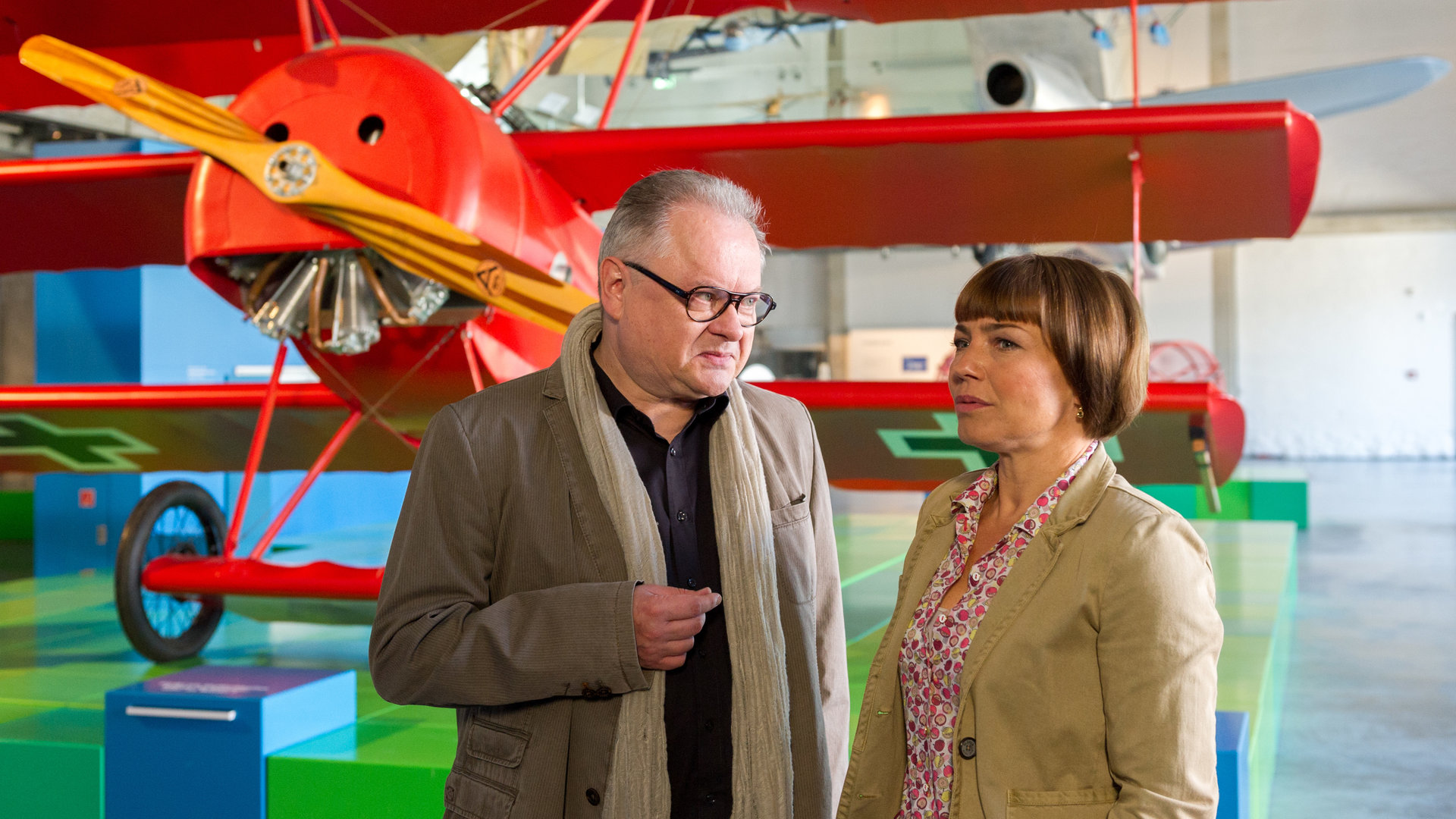 "SOKO Wismar - Die Spur der Nachtigall": Martin Steinhardt (Heinz Rudolf Kunze) und Katrin Börensen (Claudia Schmutzler) stehen vor einem roten Modellflugzeug nebeneinander und unterhalten sich. Katrin schaut in die Ferne, ihr Blick ist sehr nachdenklich.
