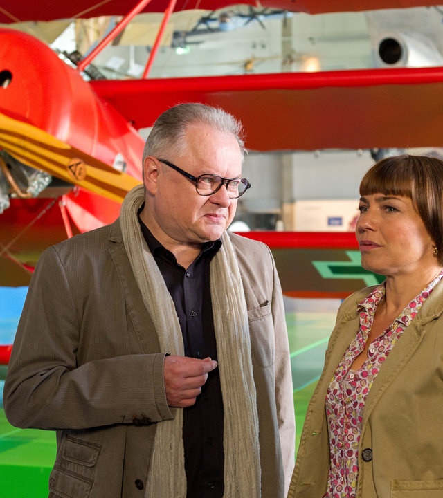 "SOKO Wismar - Die Spur der Nachtigall": Martin Steinhardt (Heinz Rudolf Kunze) und Katrin Börensen (Claudia Schmutzler) stehen vor einem roten Modellflugzeug nebeneinander und unterhalten sich. Katrin schaut in die Ferne, ihr Blick ist sehr nachdenklich.