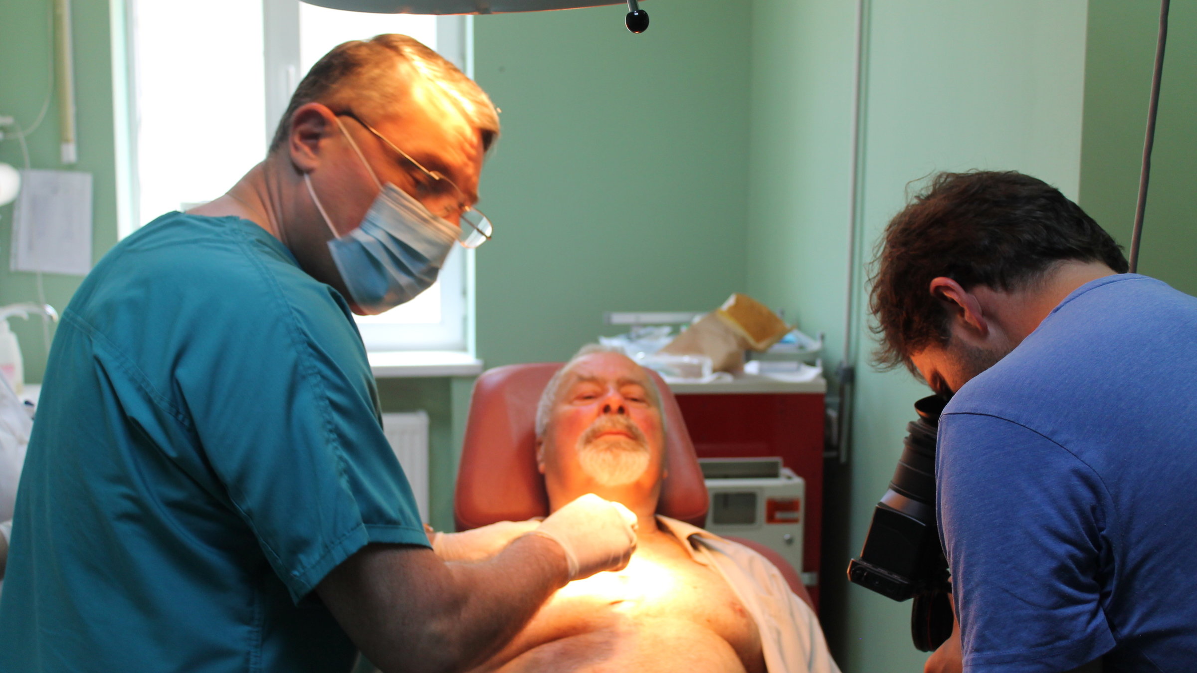 "plan b: Heilen ohne Antibiotika - Wie wir in Zukunft Infektionen behandeln können": Ekkehard Eichler liegt auf einem Behandlungstisch. Neben ihm steht ein Arzt mit Mundschutz, der ihn am nackten Oberkörper behandelt.