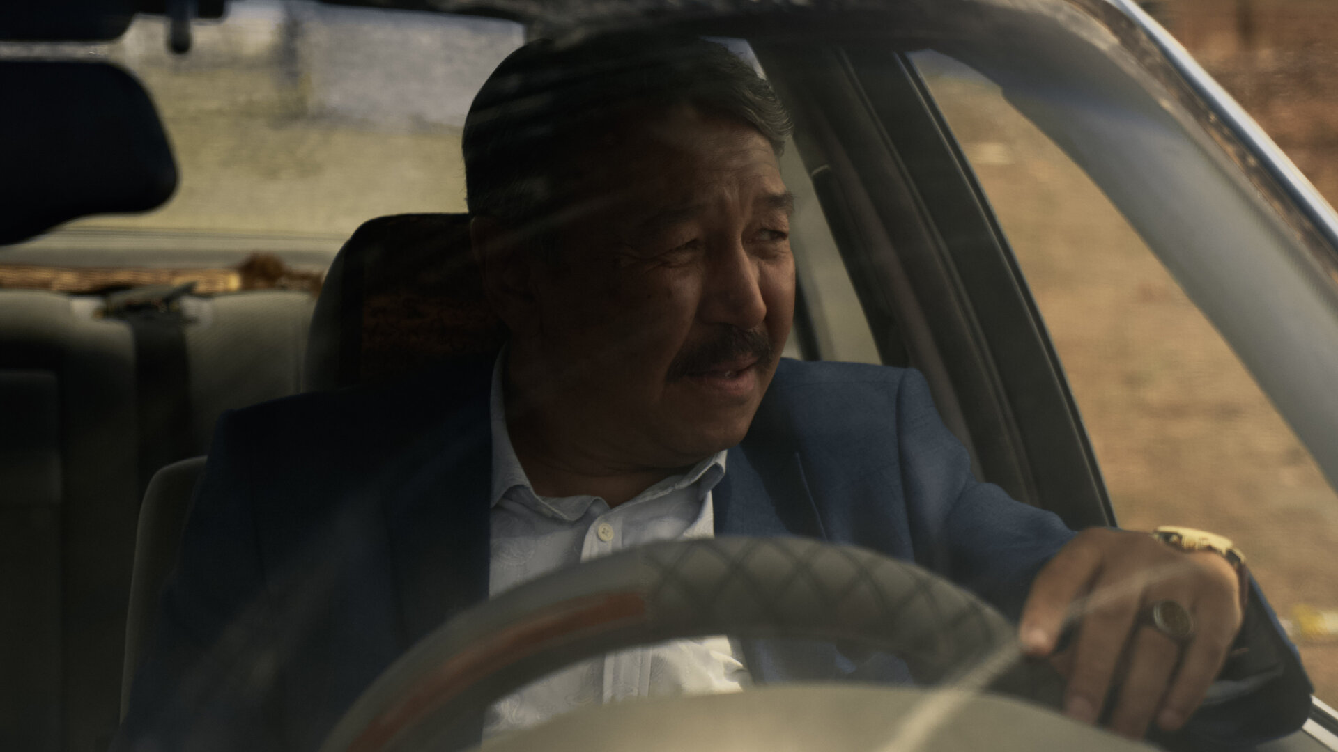 "Infiniti - Auf der anderen Seite des Spiegels": Askarev (Erken Gubashev) sitzt in einem Auto und schaut angespannt aus dem Fenster.