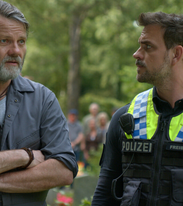 "Notruf Hafenkante - Sie ist wieder da": Die Polizisten Kris Freiberg (Marc Barthel) und Nick Brandt (Raúl Richter) stehen mit Olaf Willing (Christian Rudolf) auf einem Friedhof und unterhalten sich.